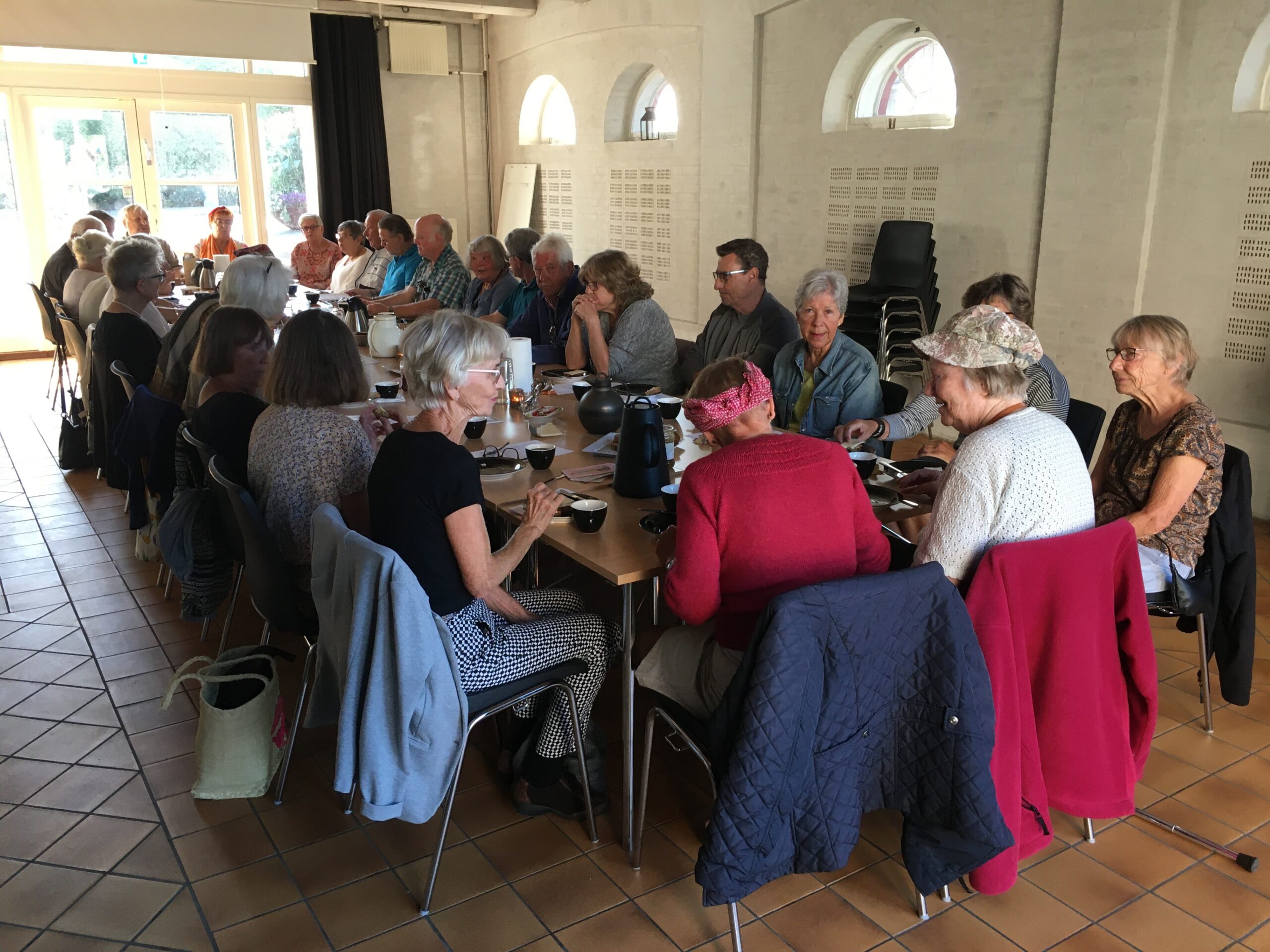Pensionister samlet ved langbord i Rejsestaldens Vognport